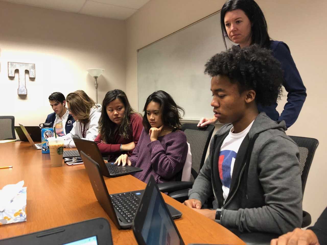 In a college application workshop, Ms. Gillespie assists seniors in matching their common application in Naviance.